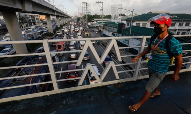 A commuter crosses a bridge overlooking slow-moving traffic in Metro Manila, Philippines.