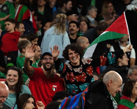 Fans, holding Palestinian flags, show their support.