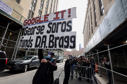 A protester holds a placard accusing Soros funding the Manhattan district attorney, Alvin Bragg, in New York on 22 March 2023.