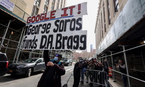 A protester holds a placard against Manhattan district attorney Alvin Bragg and billionaire investor George Soros outside Bragg’s office.