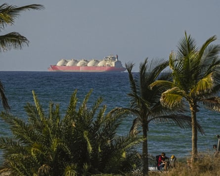 A tanker on the horizon with palm trees in the foreground
