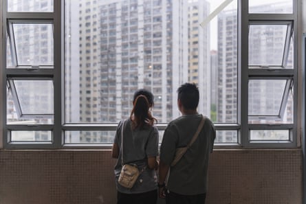 Lam Ka-Wan Karen (left) and her husband, Yip Shun-Ting, Carbon gaze out the window at the dense high-rise residential buildings.