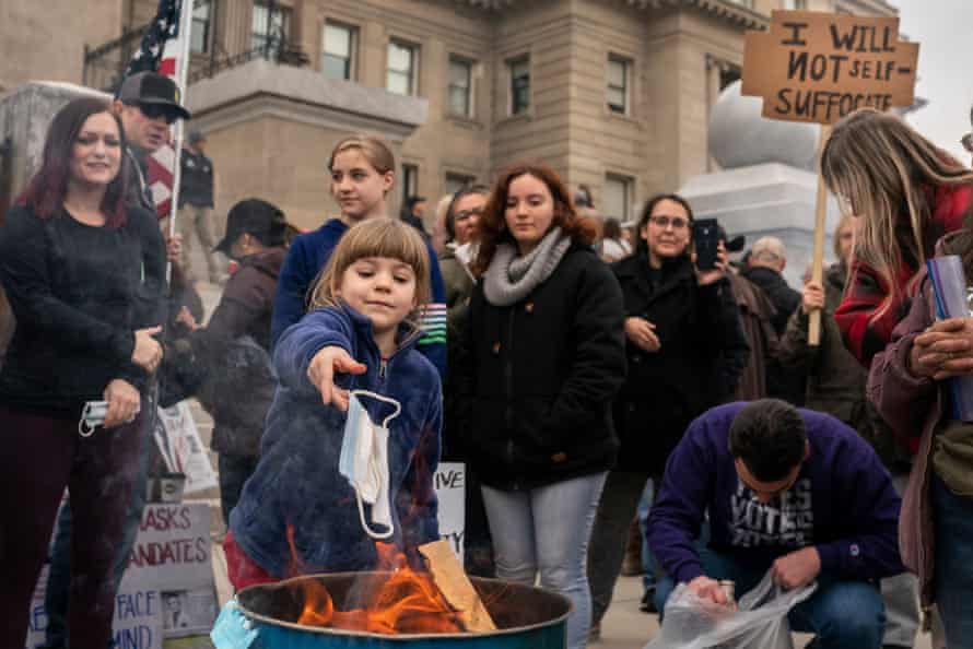 A child tosses a mask into a fire during a mask-burning event at the Idaho statehouse in Boise on 6 March.
