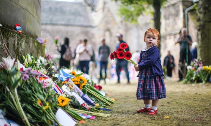 A young girl laying flowers in remembrance of the Queen outside the Palace of Holyroodhouse.