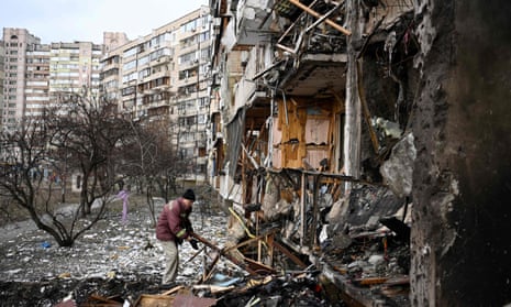 A man clears debris at a damaged residential building in a suburb of Kyiv, the Ukrainian capital.