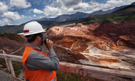 worker in hard hat looks at huge open-cast mine