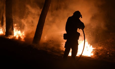 A firefighter battles a blaze north of Athens