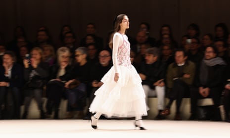 A model wears a tutu-style skirt on a catwalk with audience behind