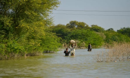 People in Pakistan wade through flood water