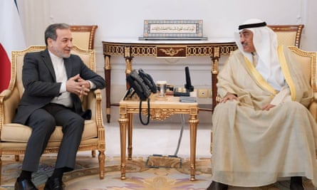 Two men sit in chairs leaning towards each other