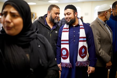 Imam Shift Ur Rehman, wearing a West Ham United scarf, talks with worshippers at Liverpool Mosque and Islamic Institute.