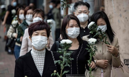 中国の元指導者に敬意を表するために菊の花を手にする女性グループ。