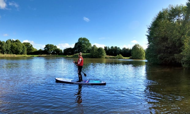 A woman paddleboards on Alderford Lake