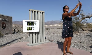 A visitor takes a selfie in front of the unofficial thermometer at Furnace Creek visitor center.