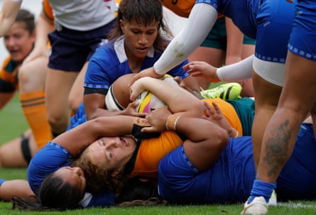 The Australia prop Brianna Hoy is held up over the try-line by Samoan tackles.