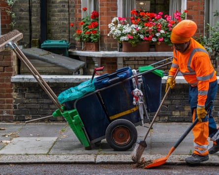 Street cleaner Winston Barrett sweeps a kerb beside his loaded rubbish cart