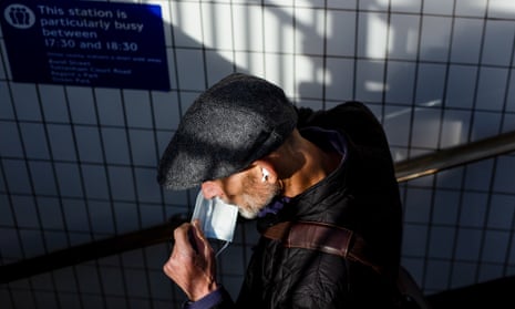 A man puts on his mask as he enters Oxford Street underground in London