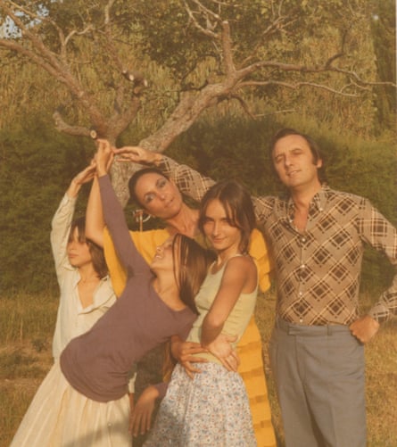 A shot from the 1960s with Rego, her son Nick Willing, two daughters, and late husband, Victor, standing together, each with a hand raised and touching, near a tree