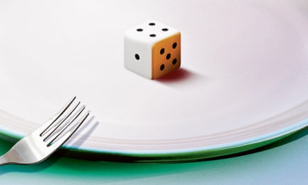 Photograph of a plate with a dice in the middle and a fork by the side
