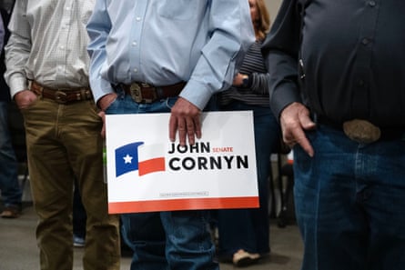 a person holds a sign in support of John Cornyn