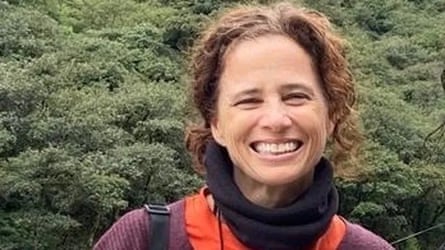 A woman smiling with trees behind her
