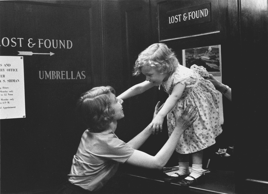 A woman picking up a child from a lost and found counter