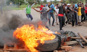 Demonstrators are behind a burning barricade on a road to Harare on January 15.