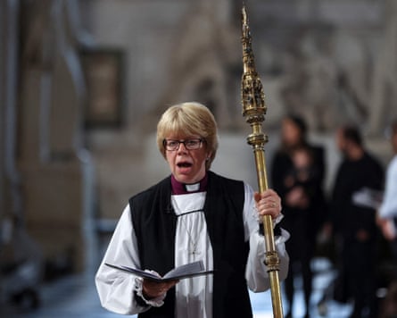 Sarah Mullally in church holding a hymn sheet and a bishop’s staff