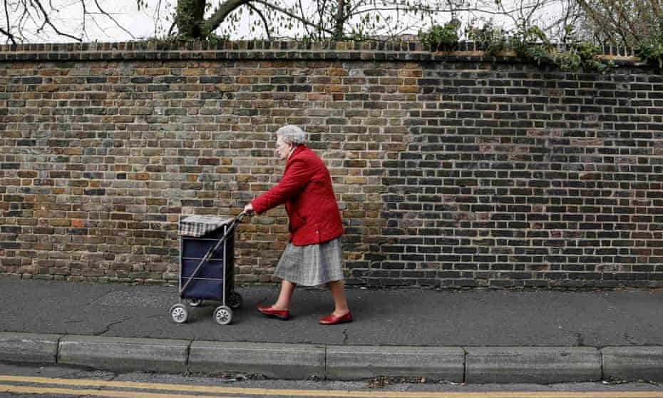An elderly woman pushes a shopping trolley