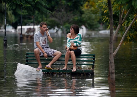 Residents sit on a bench at a flooded public square after a rainstorm in Buenos Aires in 2013.