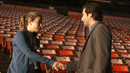The characters shake hands in an empty stand in a stadium