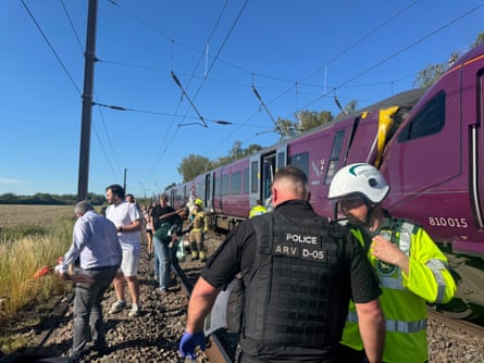 Passengers and emergency service stand on railway after train crash in Bedford