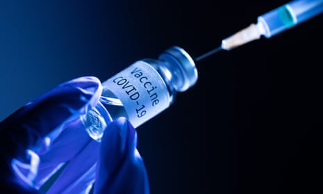 A needle is inserted into a bottle labelled Covid-19 vaccine