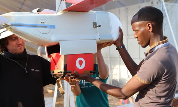 A technician from Zipline installs a cardboard box with a paper parachute in a drone in Muhanga