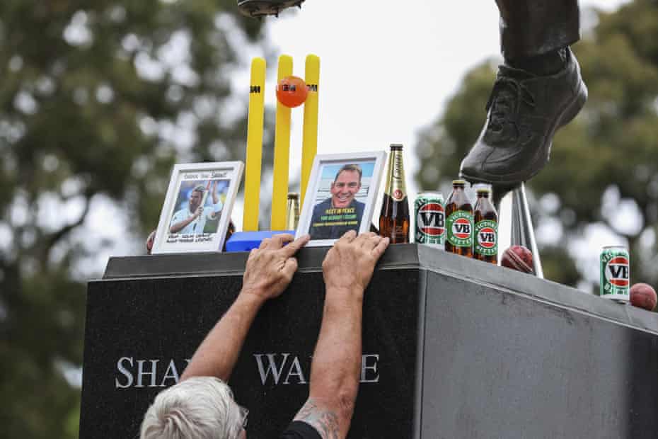 Photos, cricket balls and beer bottles are placed as tributes on Shane Warne’s statue outside the MCG.