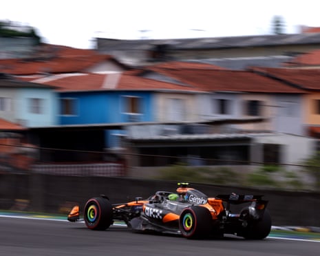 Lando Norris drives past houses on his way to victory in Brazil.