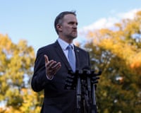 Man stands at microphones with one palm up