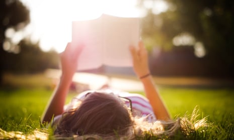 A woman reading a book lying on her back in sunlight