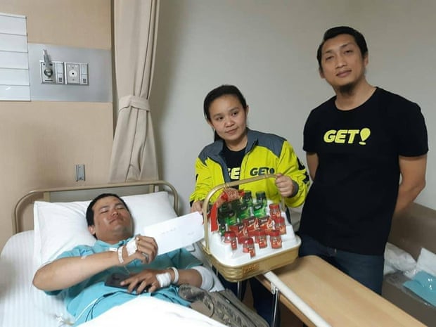 A Grab bike driver, who also works for GET, is visited by Get staff workers in hospital after he was beaten by a motorcycle taxi group in Sukhumvit 33 area.