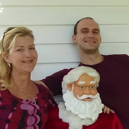 A picture of a man and woman sitting on either side of a Santa Claus statue.