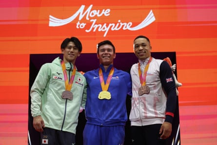 Brody Malone of the United States, center, silver medalist Hashimoto Daiki of Japan, left, and bronze medalist Joe Fraser of Britain, right, pose with their medals after the high bar.