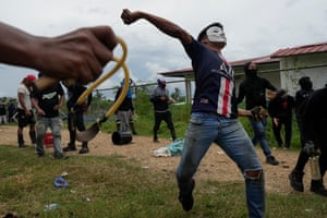 Protesters in masks throw items towards unseen people