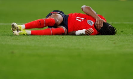 Noni Madueke lies on the Wembley turf after picking up an injury against Uruguay