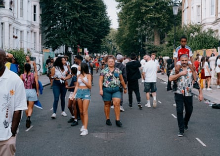 People joyfully stroll through one of Notting Hill’s affluent streets