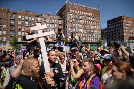 People holding a cross and religious books walk among participants in the Pride march in Budapest.