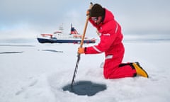 An engineer, Daniel Scholz, prepares a hole in an ice floe, with the Polarstern ship behind him.