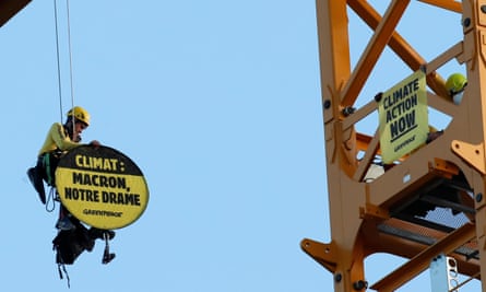 A Greenpeace activist holds a sign reading ‘Climate: Macron, our drama’ while dangling from a crane near Notre Dame Cathedral in Paris
