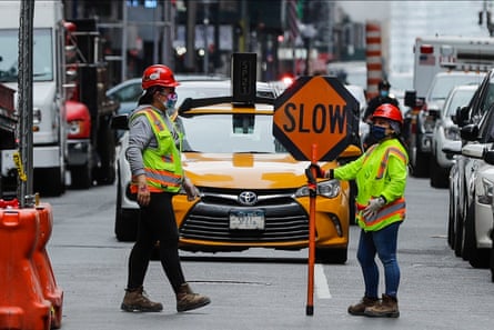 construction workers hold sign that says ‘slow’ on street