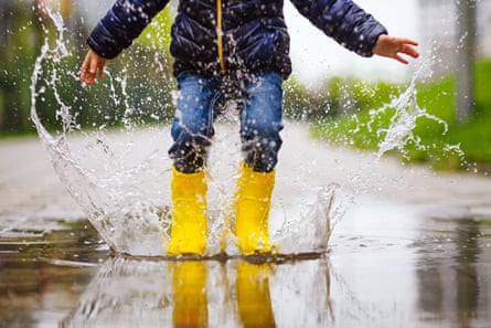 A child in yellow wellington boots jump in a puddle