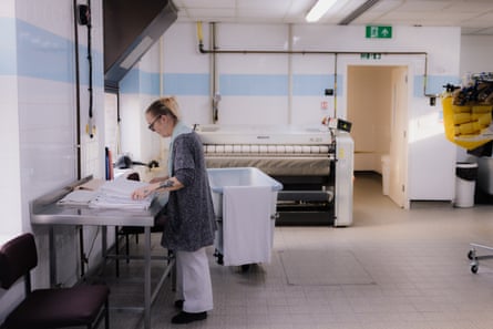 A housekeeper folding sheets in the laundry room of a care home